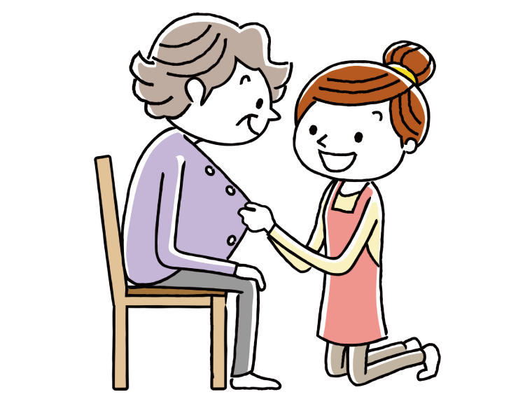 高齢女性に衣類を着せてあげている介護職員