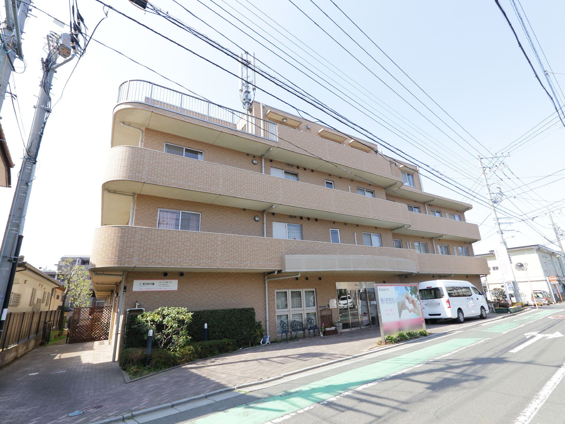 明るめの色調のレンガ風の外観をした施設。建物のエントランスには送り迎えのために十分なスペースの車止めがある。