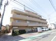 明るめの色調のレンガ風の外観をした施設。建物のエントランスには送り迎えのために十分なスペースの車止めがある。