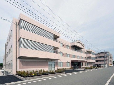 淡いピンクの外壁にすっきりとした佇まいの３階建ての当施設は、道路から館内まで段差なしのバリアフリー構造である。