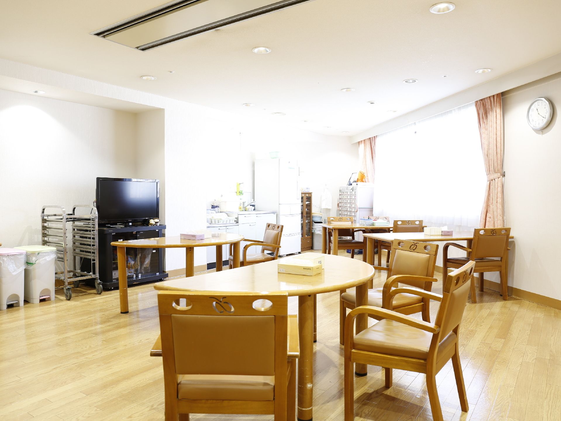 談話室には半円型の3人掛けテーブルと四角形の4人掛けテーブルがあり、椅子には背もたれとひじかけがある。テレビも設置されている。