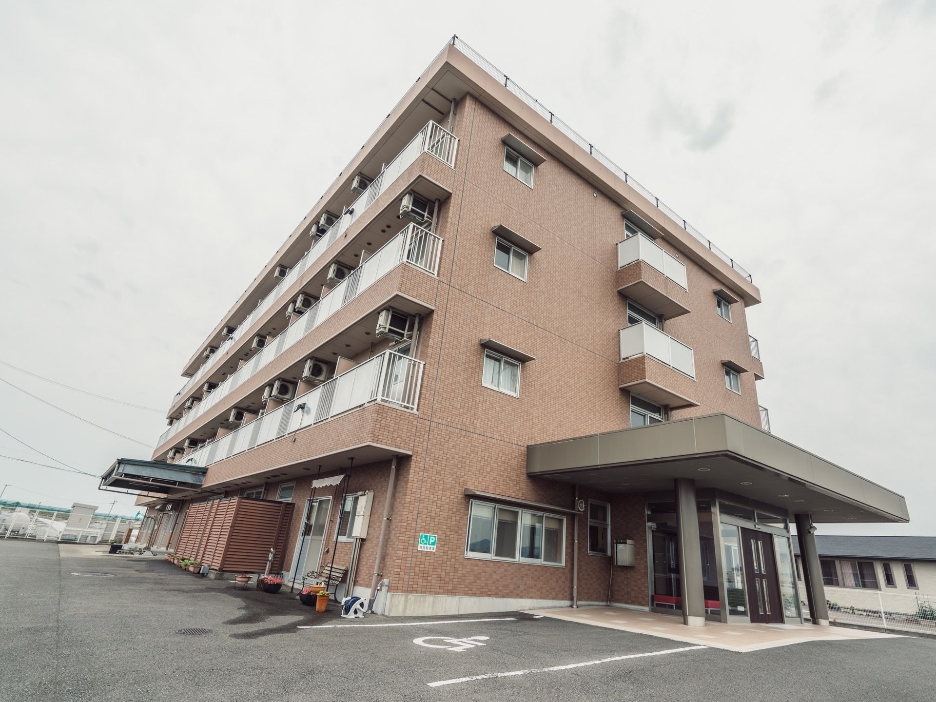 施設建物を屋や斜めから見上げたところ。各居室の前にエアコンの室外機が取り付けられているのが見えている。