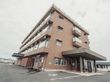 施設建物を屋や斜めから見上げたところ。各居室の前にエアコンの室外機が取り付けられているのが見えている。