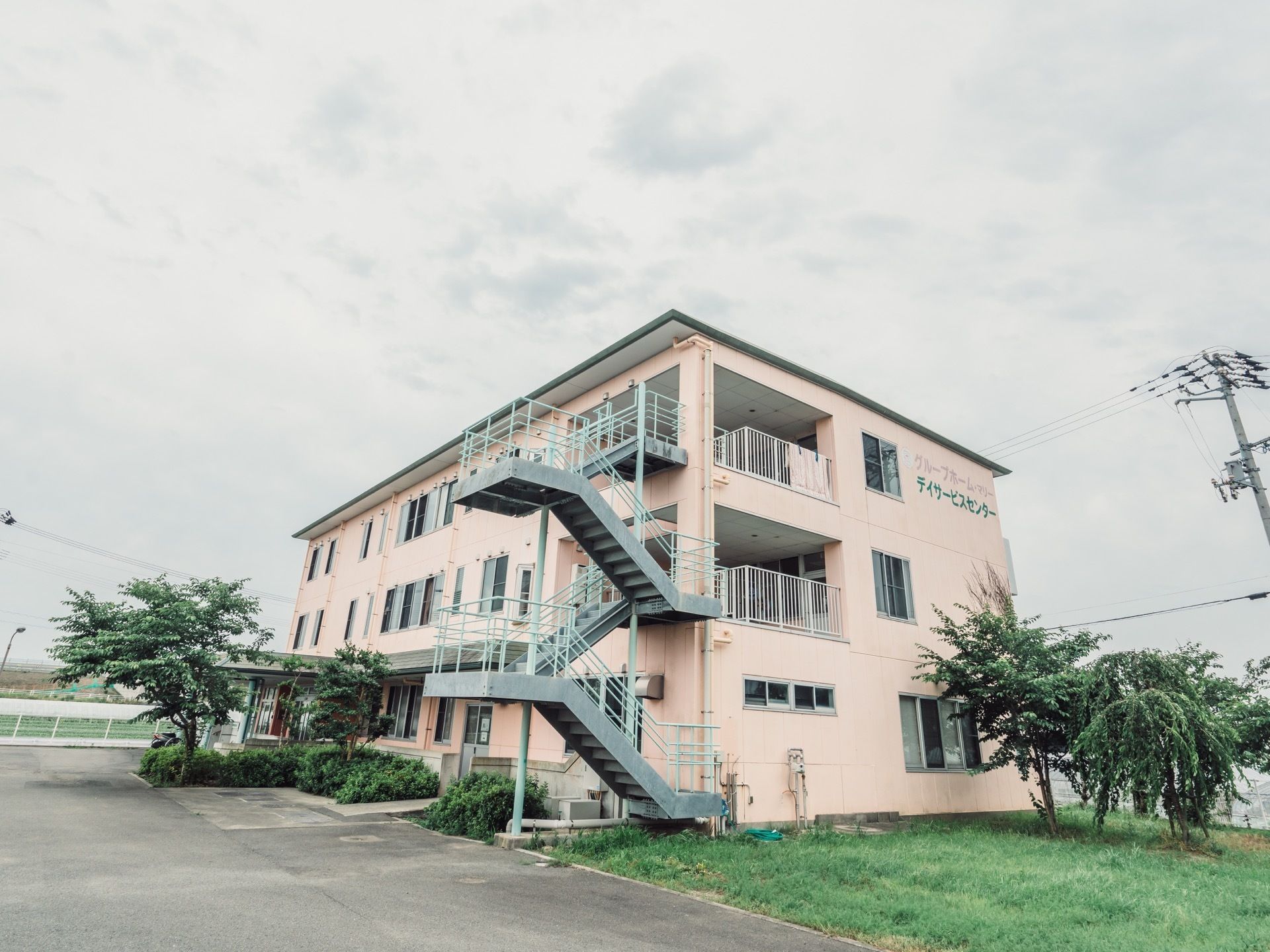 建物には幅の広い非常階段がある。バルコニーではシートを干すことができる。敷地内には草木が育てられている。