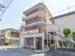 住宅街の一角にあるレンガ風のタイルが貼られた鉄筋コンクリート造の4階建ての建物。1階外壁には施設名が入っている。