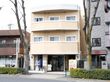 鉄筋コンクリート3階建ての建物。外壁は周りとの調和を考えたクリーム色。施設玄関は道路側に面している。
