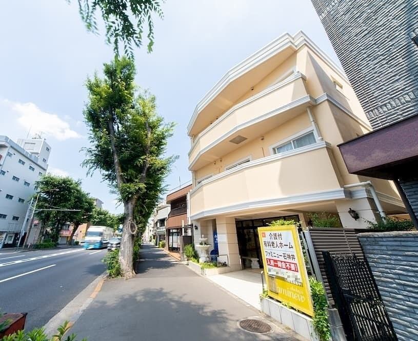 1本の大木の奥にはベージュと白を基調とした3階建ての建物