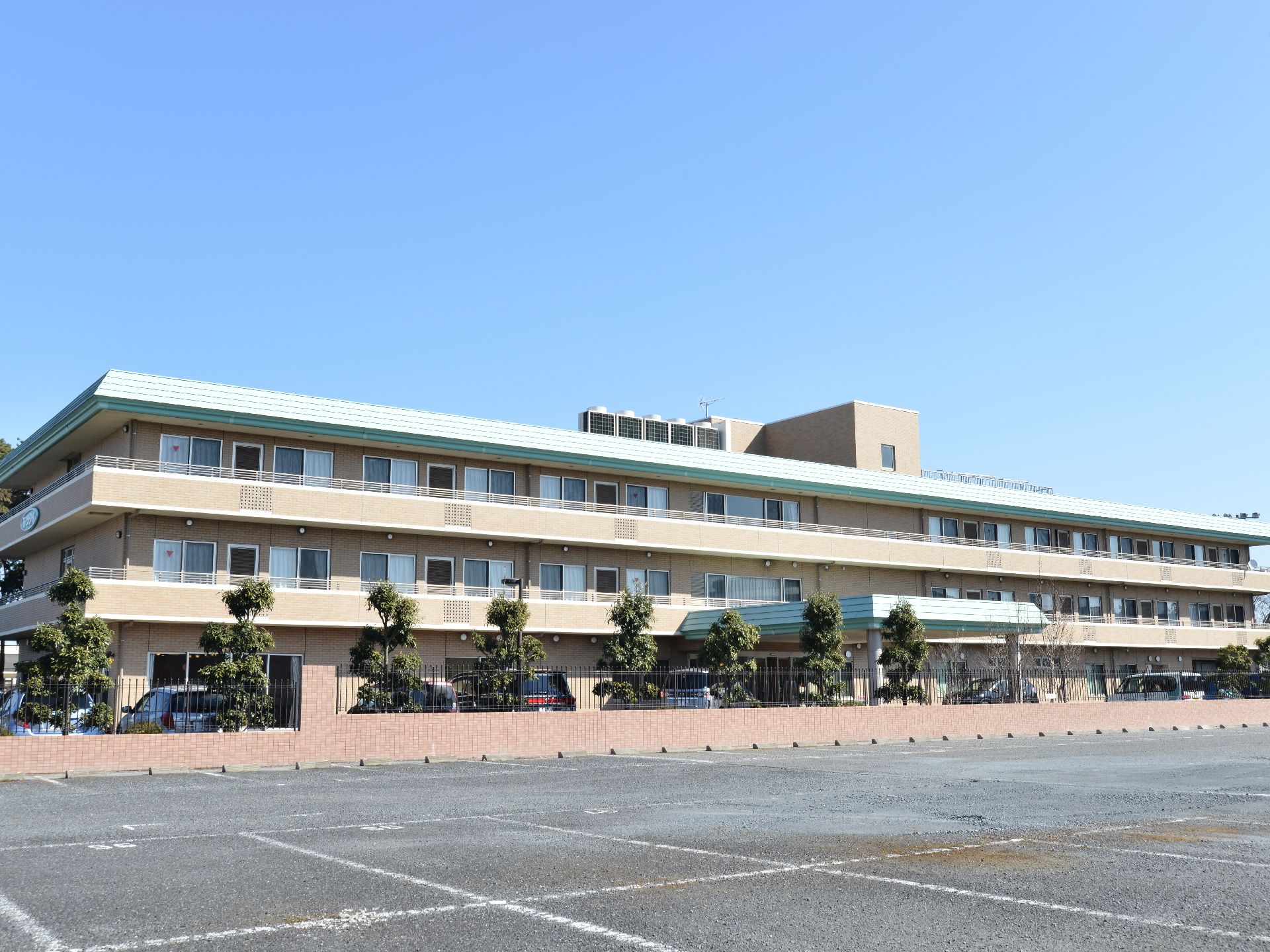 外観はベージュ色で落ち着いた色味となっている。3階建ての広い建物。駐車スペースも広いので、家族も来やすい。