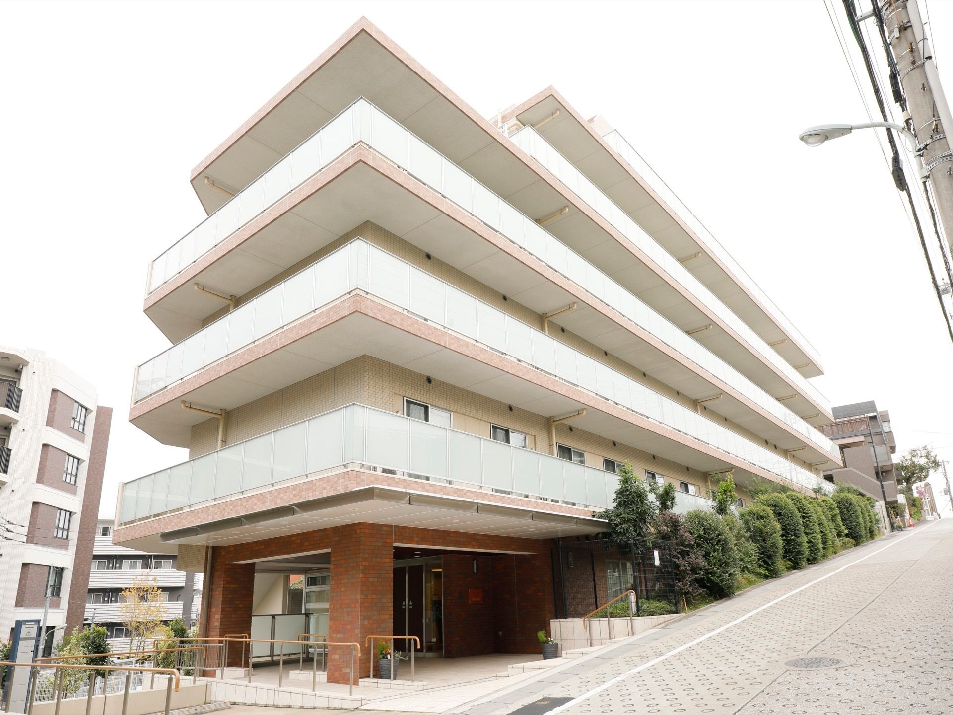 坂道に面して建てられた鉄筋コンクリート造りの施設。最も下の階はエントランスになっており、坂道に沿って植栽が施されている。
