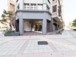 施設1階前には広々とした歩道があり、間隔をあけて木が植えられている。建物2階のところに施設の看板がある。