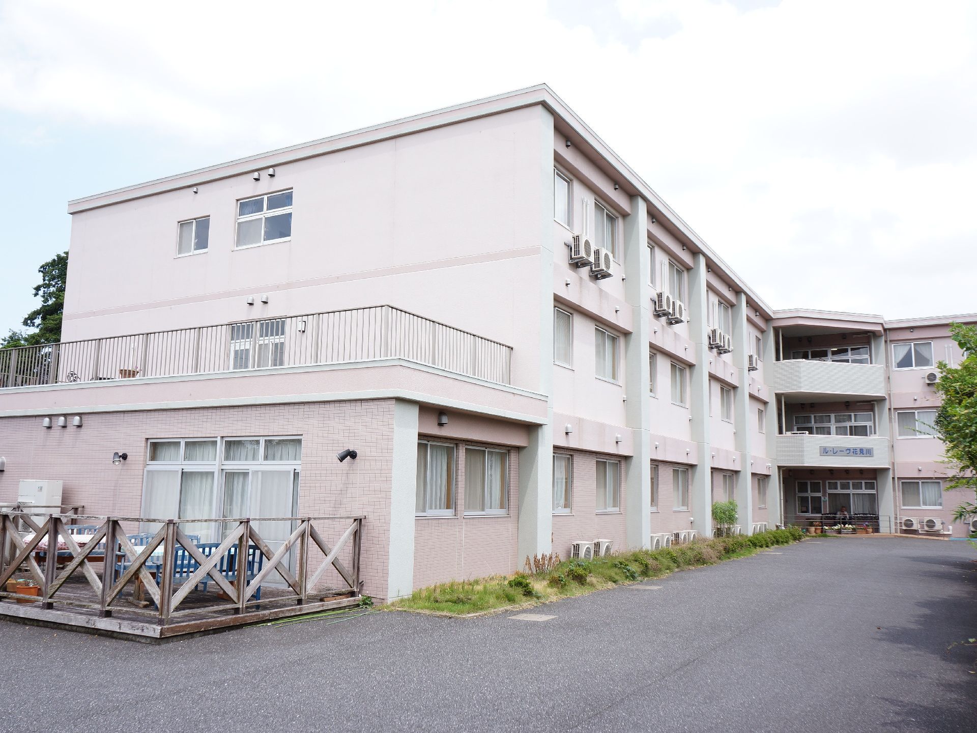 建物の外観は薄いピンクを基調としており、見るものに安心感を与えている。3階建てになっており、建物の前には緑も植えられている。
