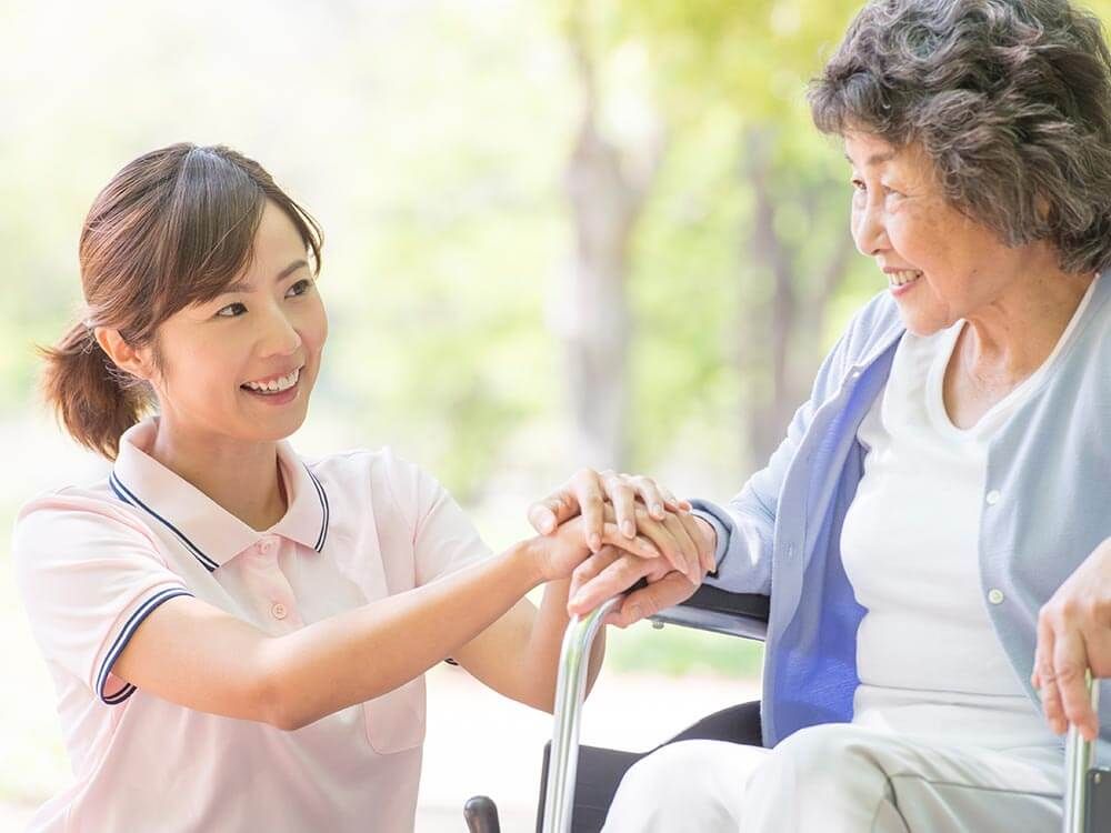 外で手を組みながら横にいる男性を見つめる高齢の女性