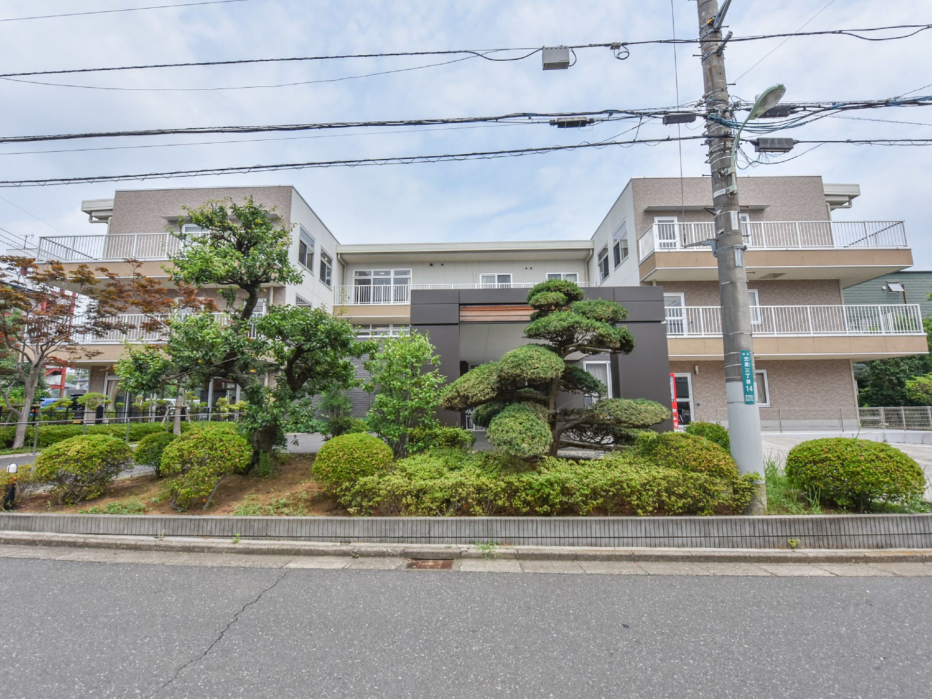 綺麗に剪定された庭木は、季節ごとに違う色が見られ、その奥の建物がこちらの施設である。季節ごとに違う姿を見せる。