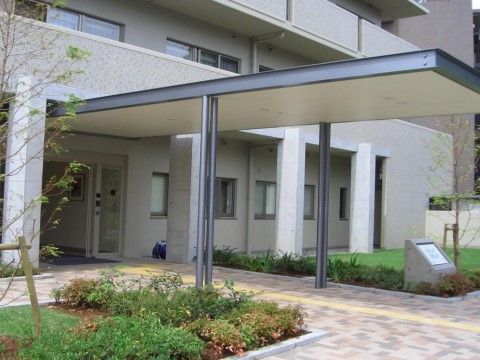 玄関から突きだした長いひさしが特徴的である。玄関の通路脇には芝生と庭木が植えられている。ひさしの手前にある石碑に施設名が入っている。