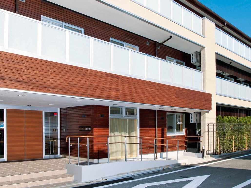 通りに面した3階建ての建物。入口へのアプローチは手すり付きの階段とスロープの両方が設置されているので安心である。