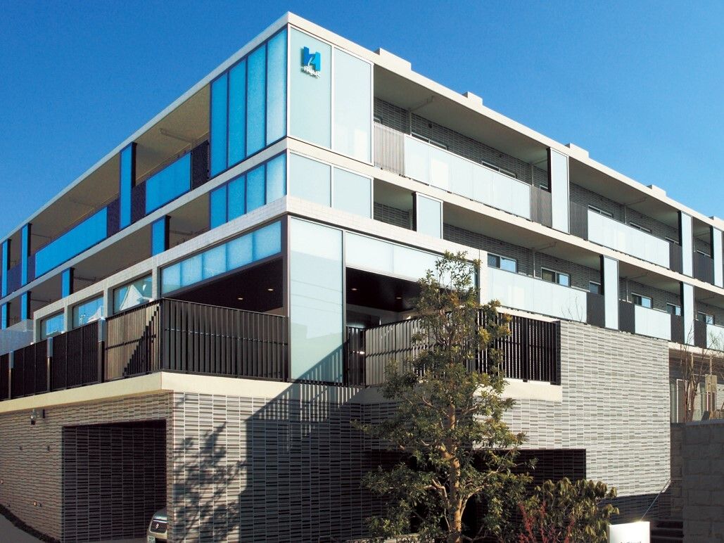 坂になった敷地にそびえる４階建ての施設。玄関までは緩やかな坂になっているが、段差もなくバリアフリーになっている。