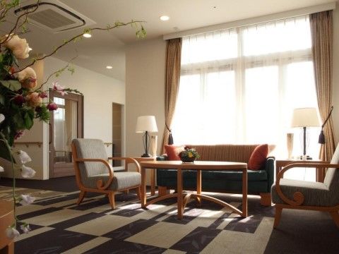 モノトーンカラーの絨毯が敷かれている。テーブルとソファが置かれている。花が活けられており、穏やかな空間である。