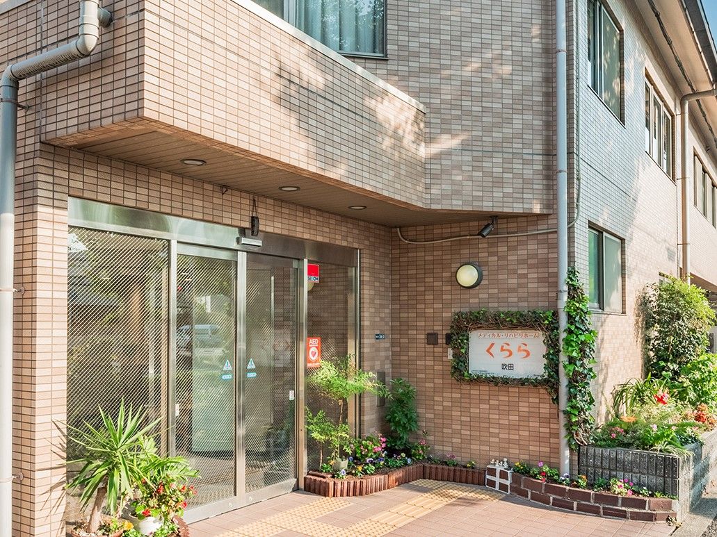 1階に駐車スペースを設け、上部の壁に施設看板を設置した3階建ての施設外観