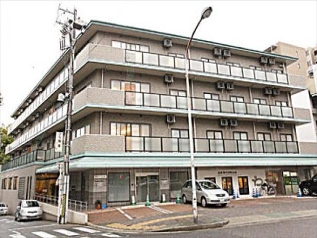 前方に複数台の駐車スペースが設けられた4階建ての建物