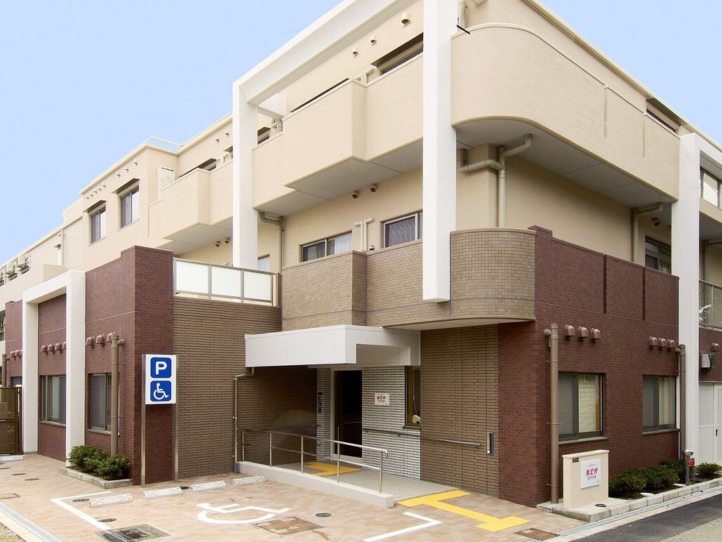 ベージュとブラウンのシックな施設建物と広めに取った車椅子乗降スペース