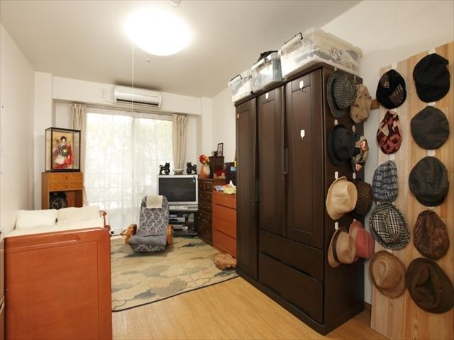 大きさの異なるタンスが数台置かれており、壁には帽子がコレクションされている居室