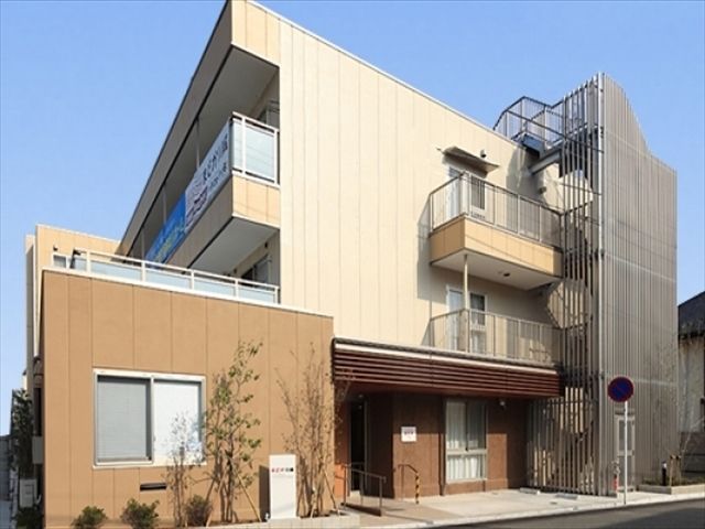 玄関前にスロープと駐車場があり、非常用階段の設置された3階建ての建物
