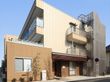 玄関前にスロープと駐車場があり、非常用階段の設置された3階建ての建物