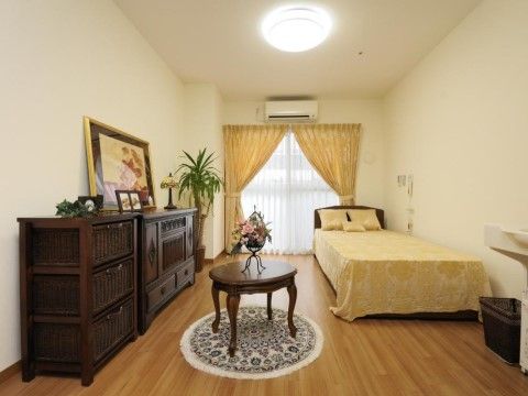広々とした明るい居室である。ブラウン系の欧米風のベッドやチェスト、テーブルを完備したゴージャスな空間である。