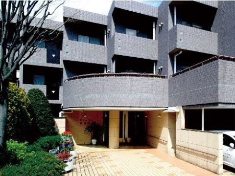 外壁がグレーのタイルの三階建ての建物と、ベージュ色のエントランス