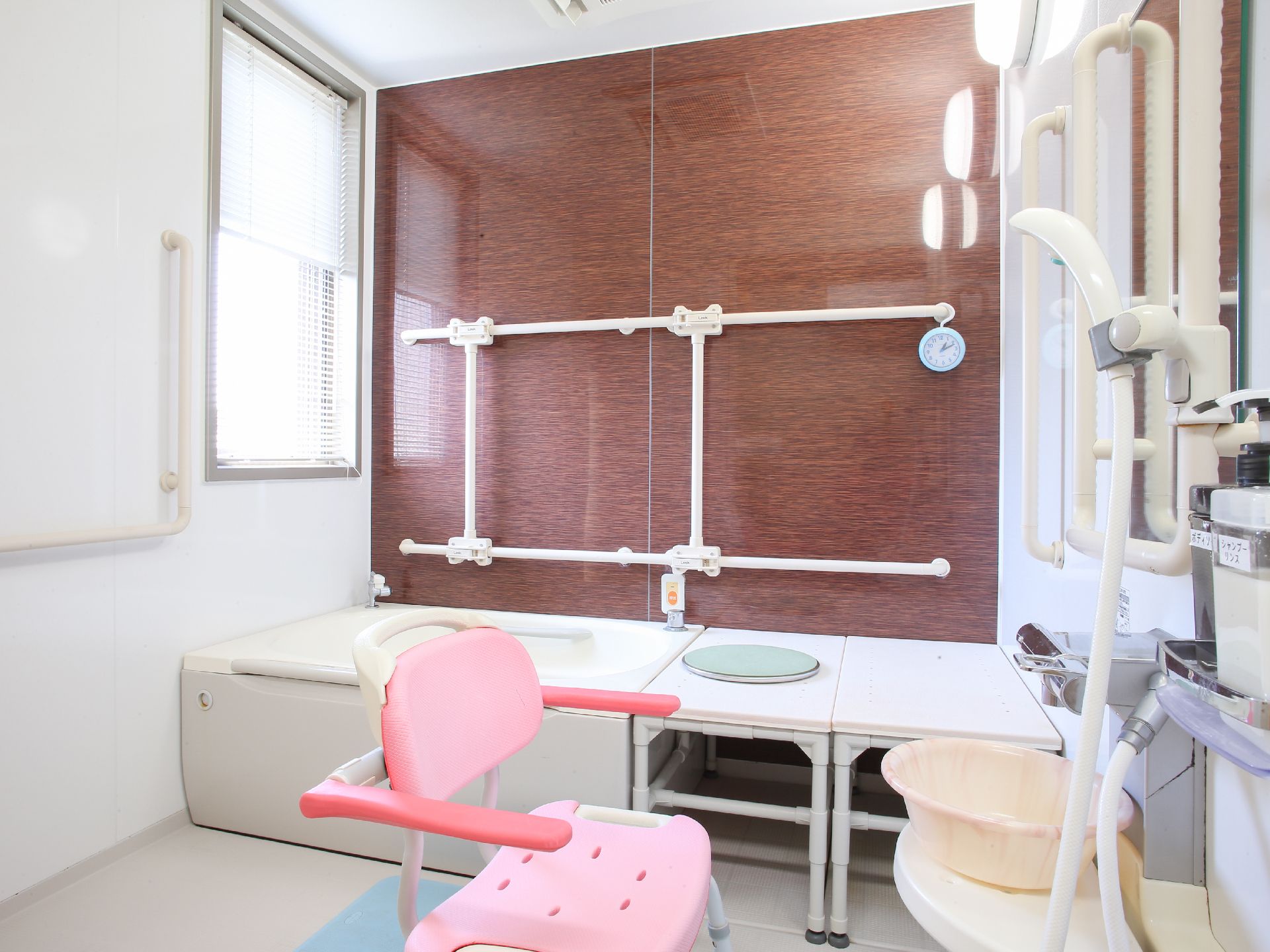 右側にはシャワーがあり、その手前には介助椅子が置かれている。左奥には湯船がある。そこのそばには手すりが付いていて、緊急用の装置がある。