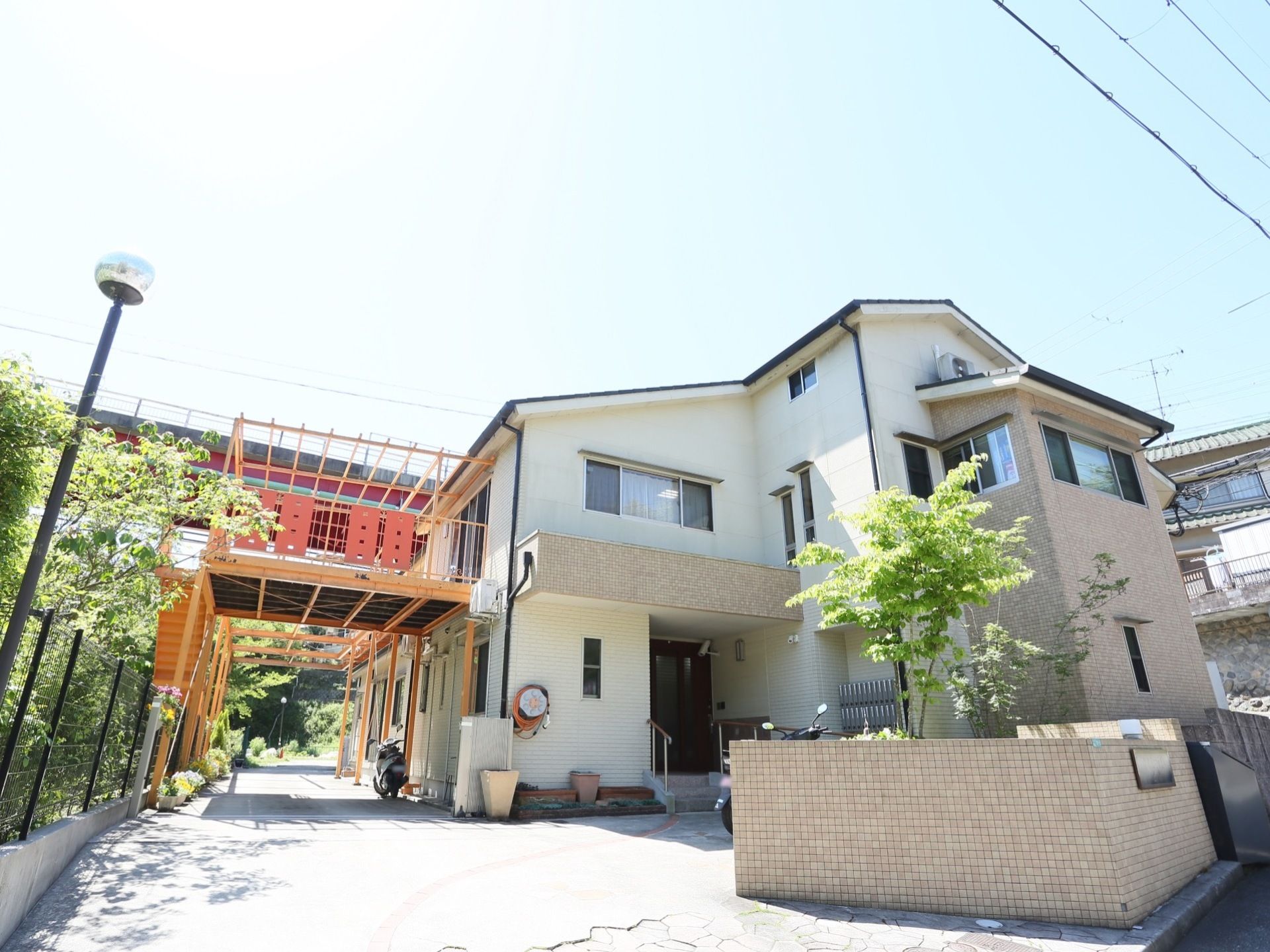 施設は外壁がベージュ色でオレンジ色の外階段が設置された２階建ての建物である。木々が植えられており、自然に親しみながら過ごすことができる。