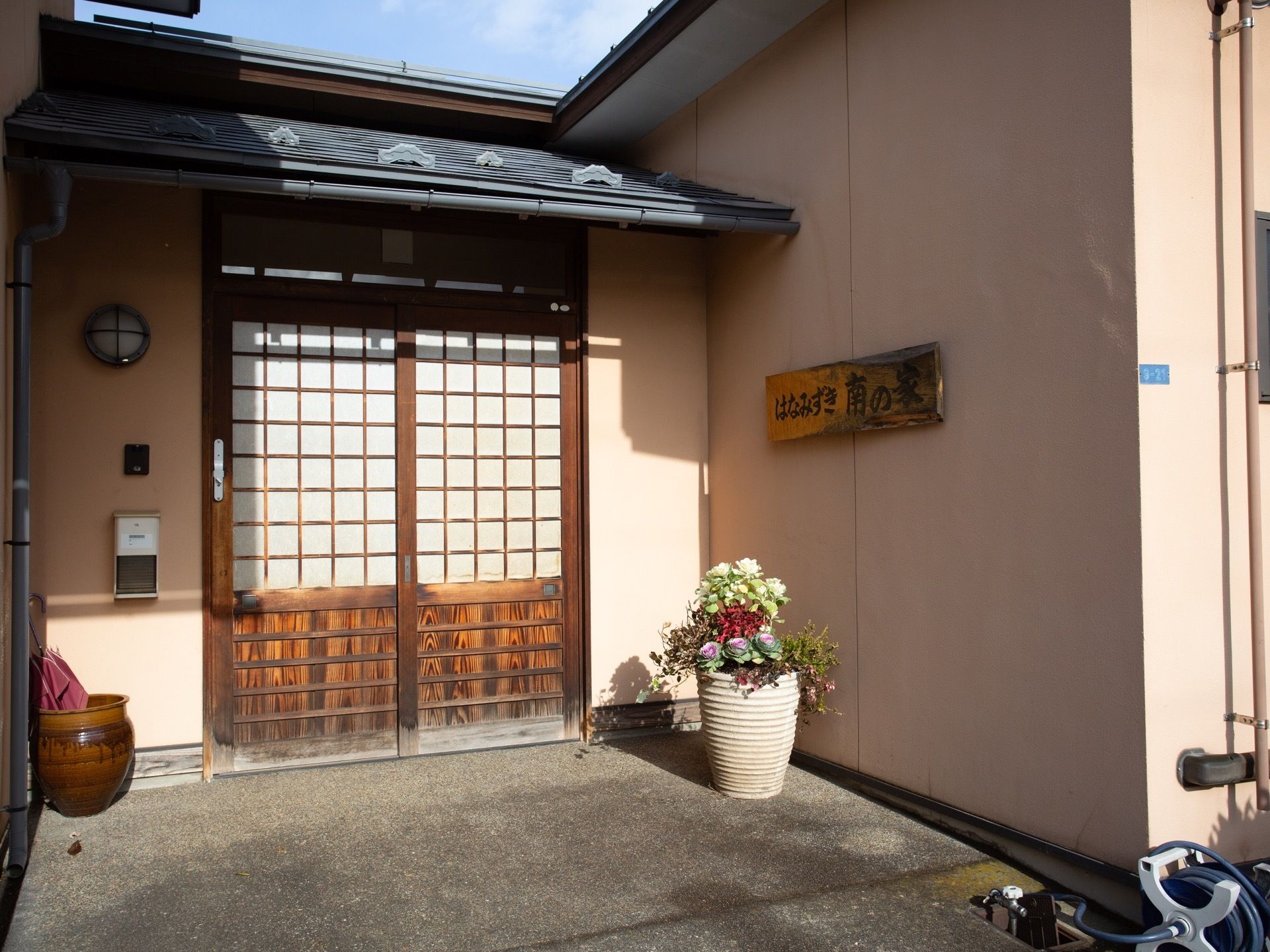 エントランスのドアは引き戸になっていて、出入りがしやすい。色とりどりの植物の寄せ植えが置かれ、家庭的な印象になっている。