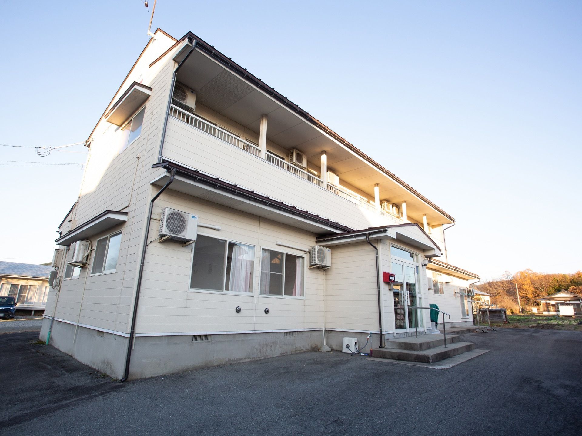 青空が広がっており、２階建ての建物が建っている様子である。周囲は舗装されており、広い空間となっている。
