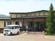 平屋建ての建物には瓦屋根が付き、玄関先には手すり付きのスロープと階段が付いている。