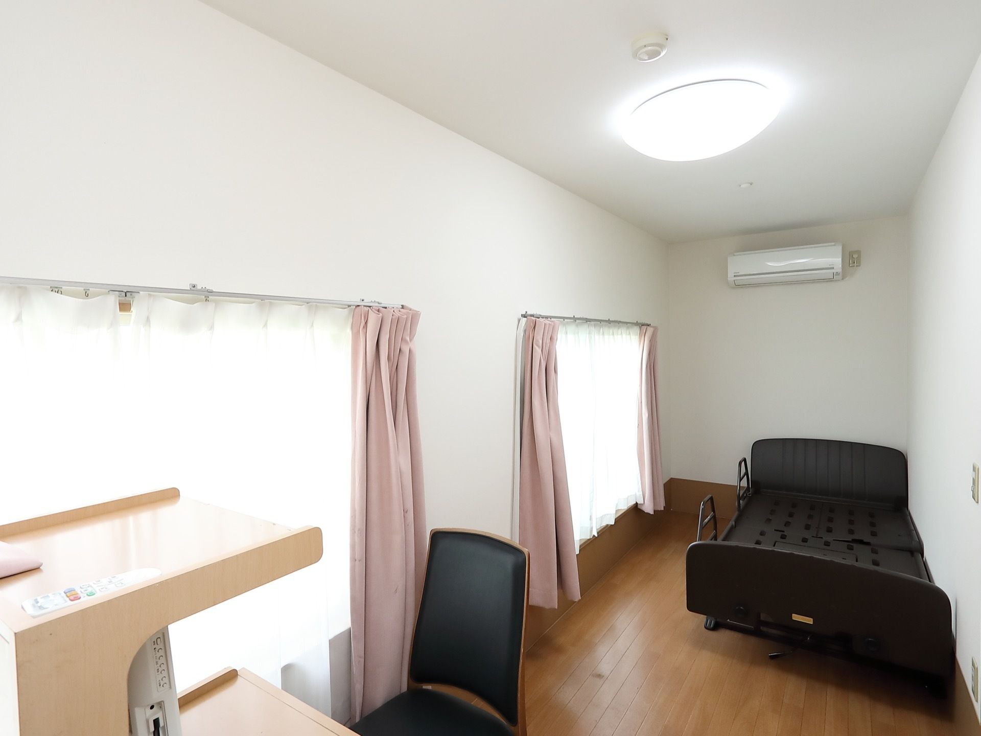 日当たりが良く、窓からは日の光が差し込んでいる。部屋にはベッドが置かれており、エアコンや照明が完備されている。