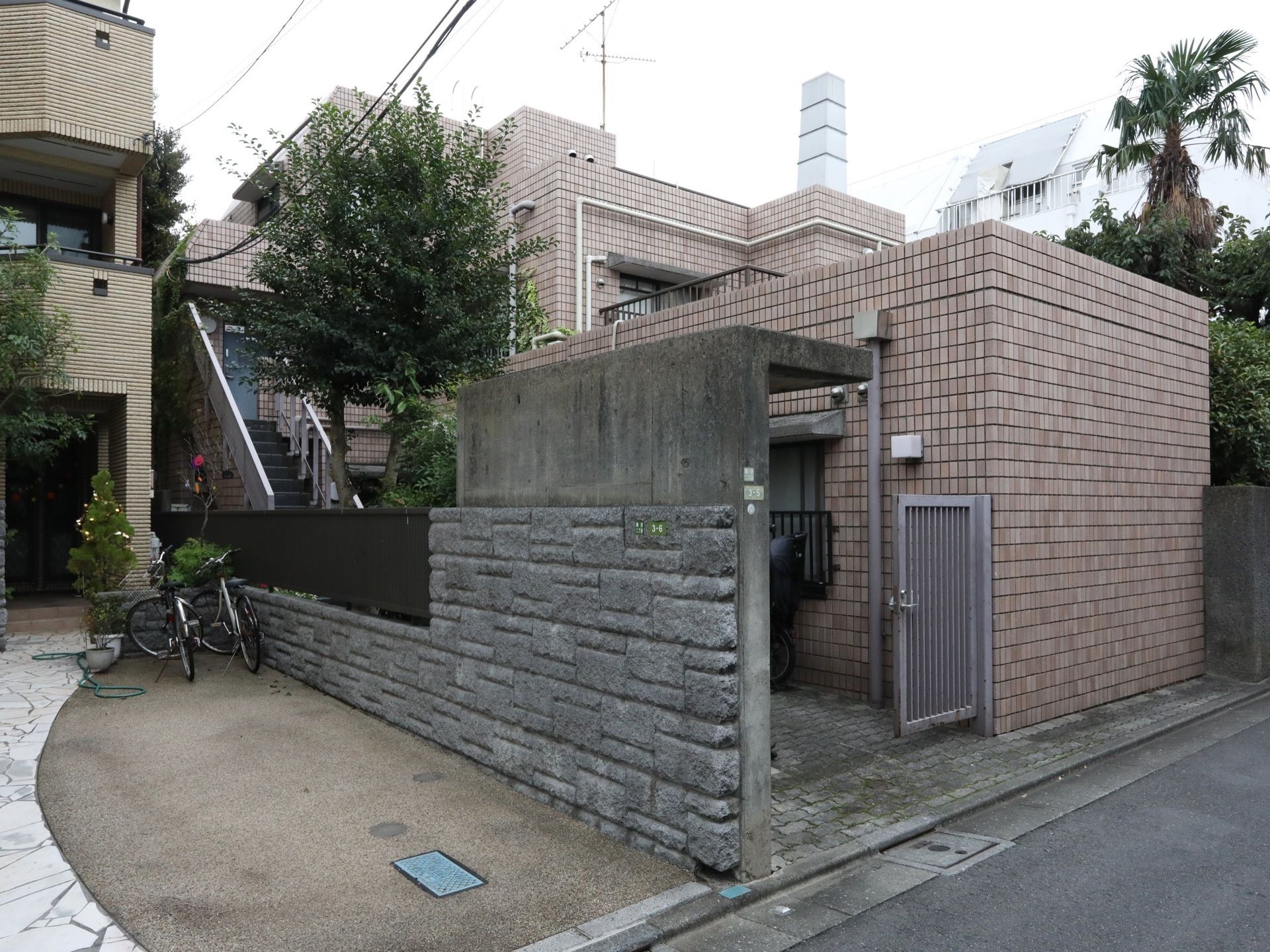 門を抜けるとコンクリートで造られた屋根が続いている。レンガ造りの建物に植えられた樹木が良い景観である。