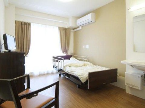突き当りに掃き出し窓があり、室内は明るい。窓に頭を向け壁際にベッドが置いてある。ベッドの上にはエアコンが設置してある。