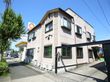 街中に建っているアパート風の外観のグループホーム。外壁の前面にホームの名称が書かれているのが見える。