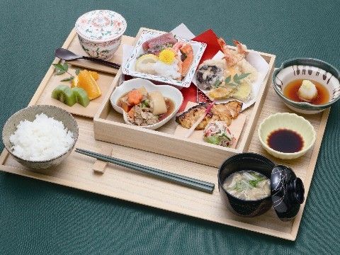 松花堂弁当風に盛り付けられ、おかずやフルーツのお皿も載っている食事プレート