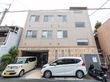 三階建ての建物の前に止まっている２台の車