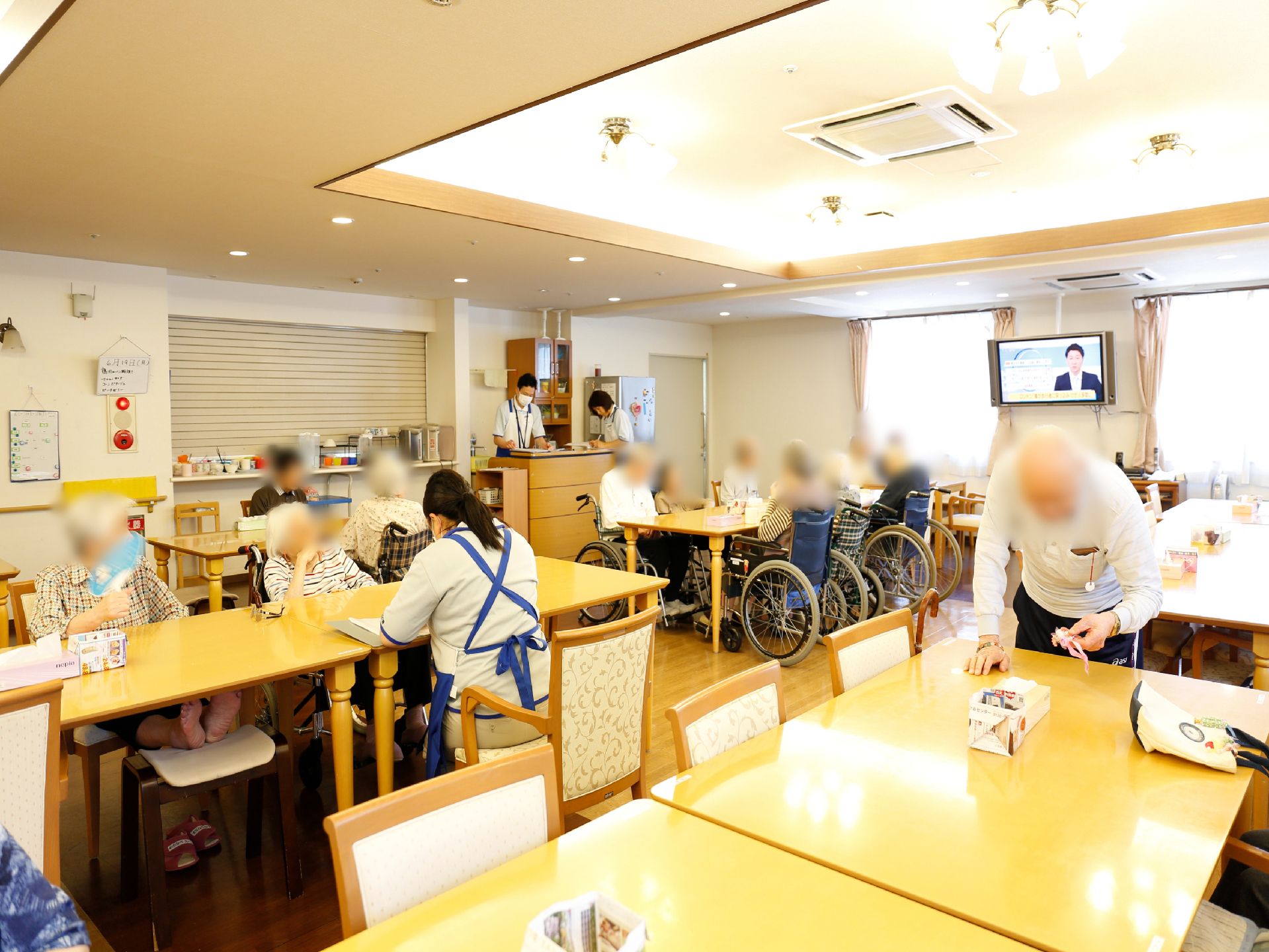 リビングには、テーブルが立ち並んでいる。車椅子の方が座れるようなテーブルも用意されており、テレビもある。