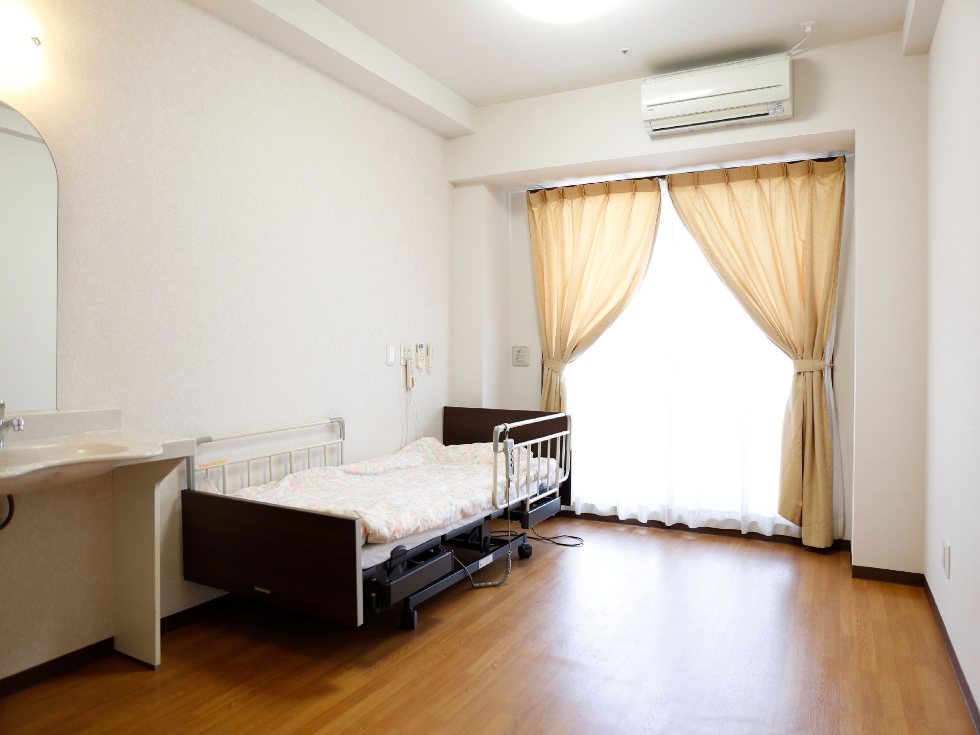 部屋は木の床であり、壁は真っ白となっている。ベッドが設置されており、さらにはエアコンも完備している。