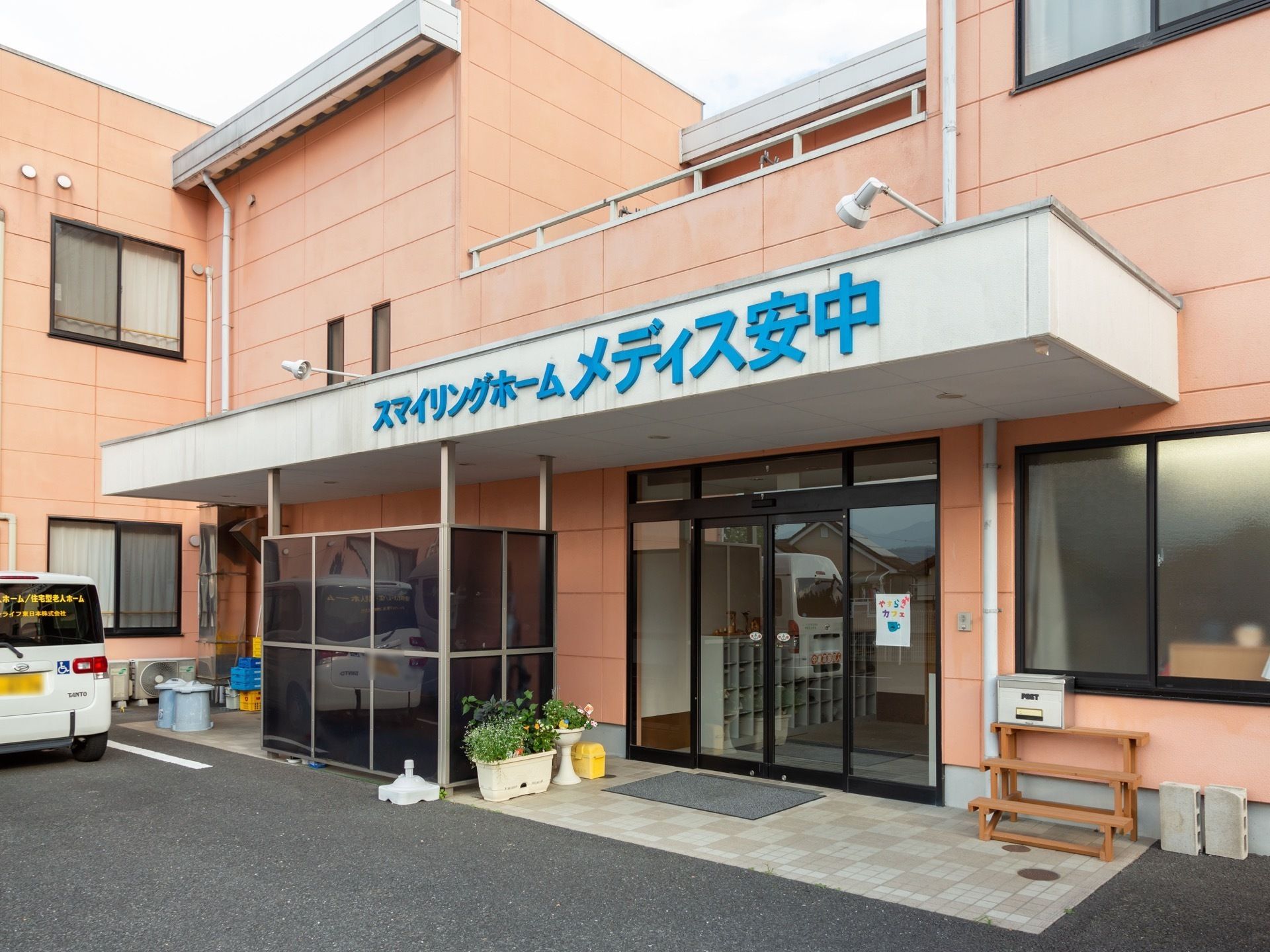 玄関は自動ドアになっている。ドアの前には玄関マットが敷かれ、花の植えられたプランターが置かれている。