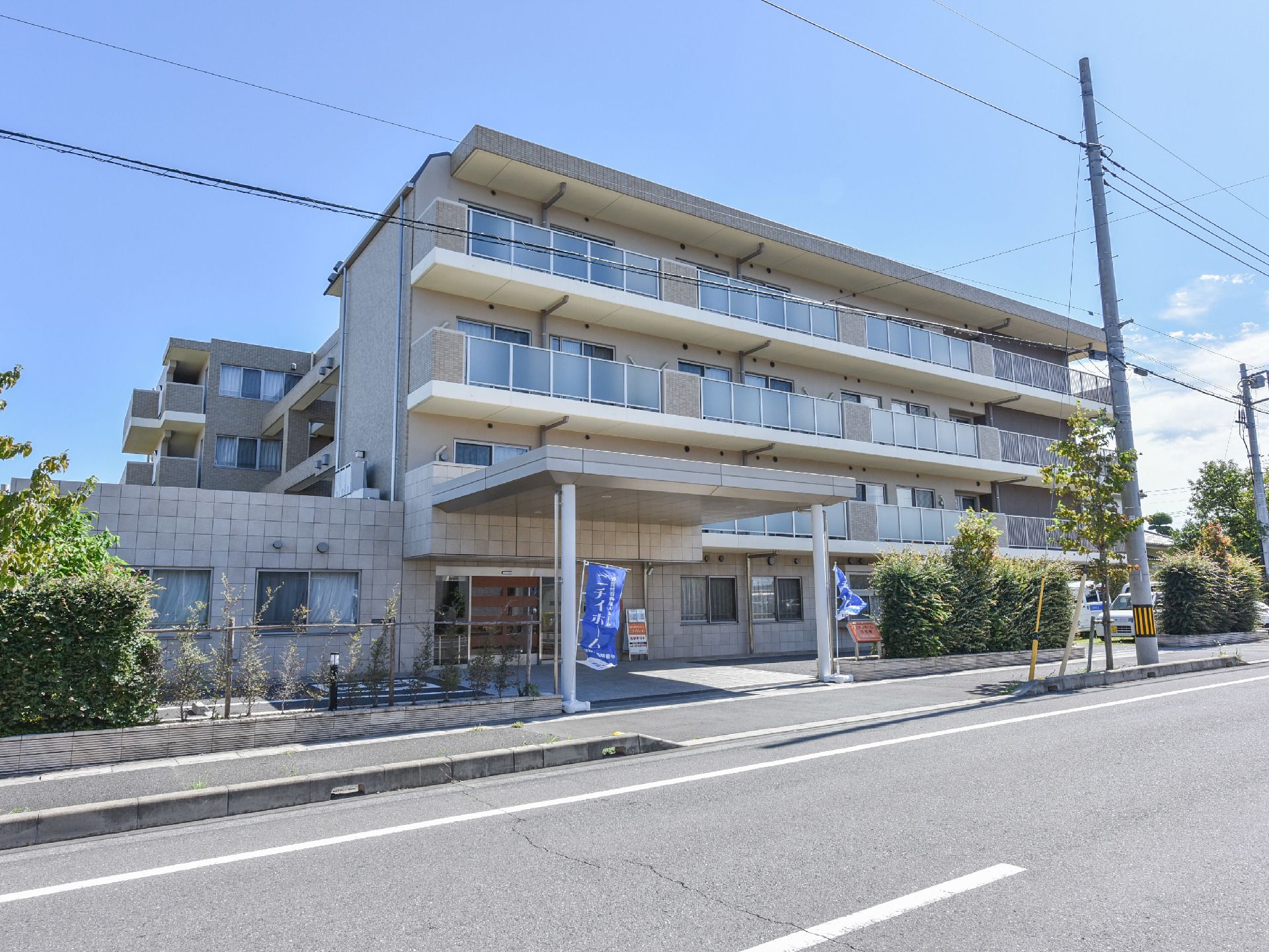 白い4階建ての建物。メイン道路に面していて大きなのぼりが立っているので初めて来所する方でもよくわかる。2階から4階はベランダが完備してある。