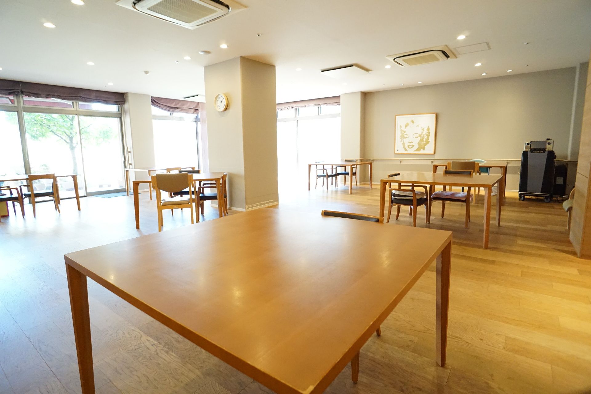 木製の四角い机が置かれた白い柱のある広間