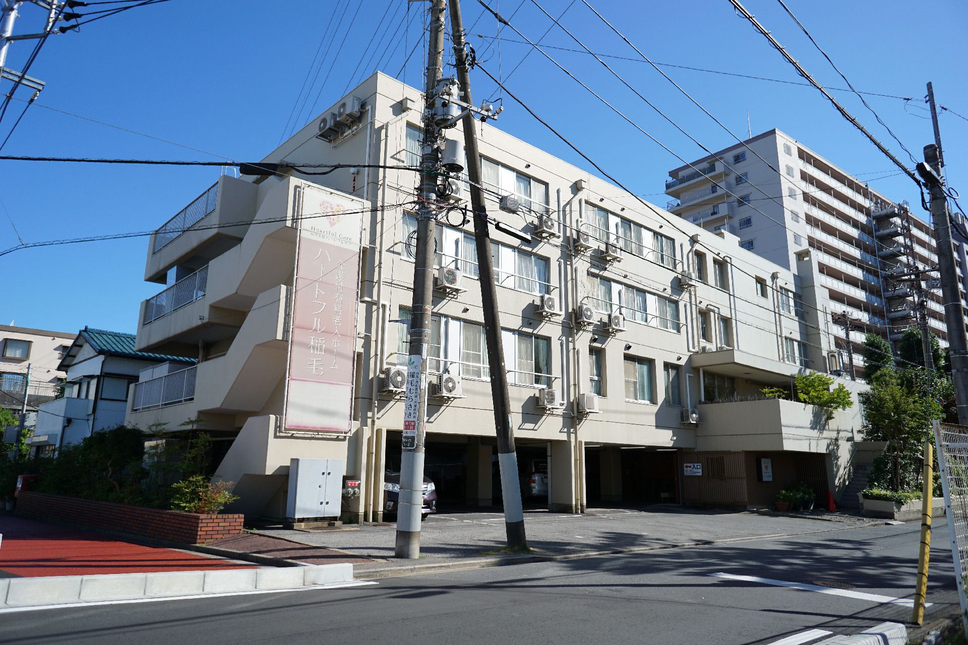 車道に隣接している白い外観の４階建ての建物