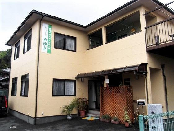 一軒家のような大きめの建物の写真。入り口付近に植物が置かれている様子