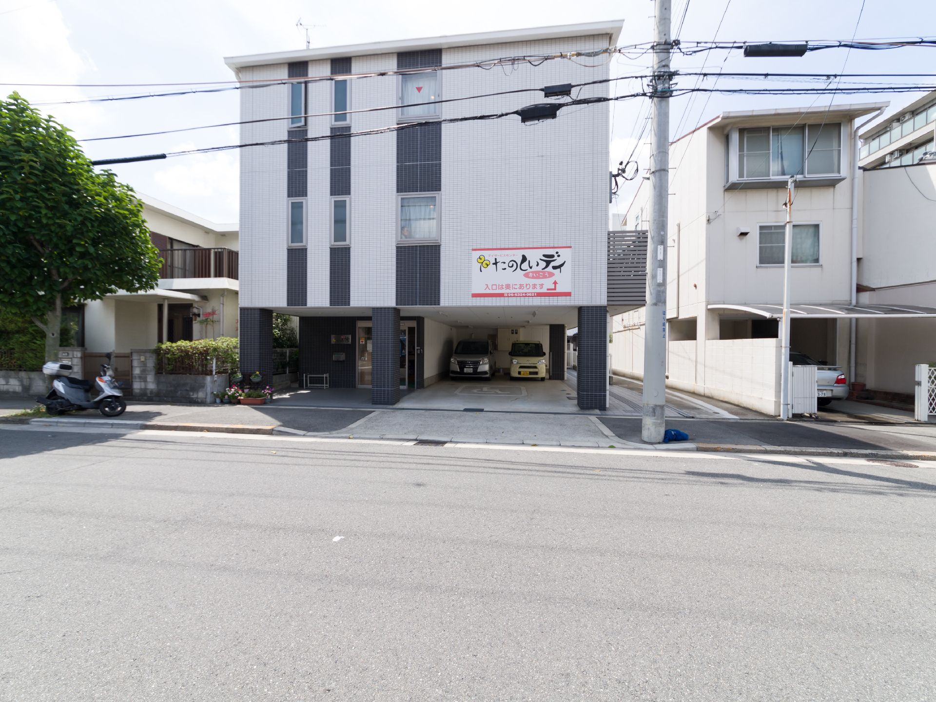 正面から見ると施設の形は四角い3階建てである。1階の半分は駐車場になっている。外壁はシックな色合いになっている。