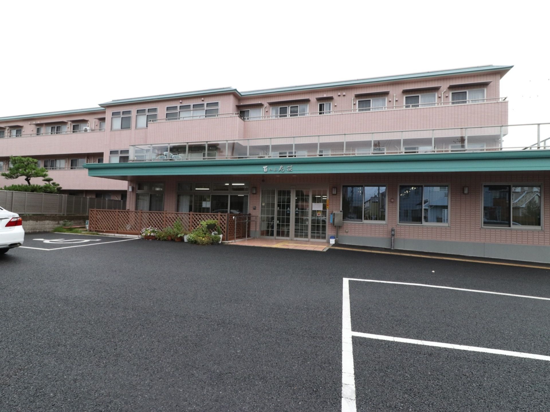施設の建物は3階建てで、上階にはベランダを設置している。壁の色は淡いピンクで、屋根部分にはグリーンを使っている。