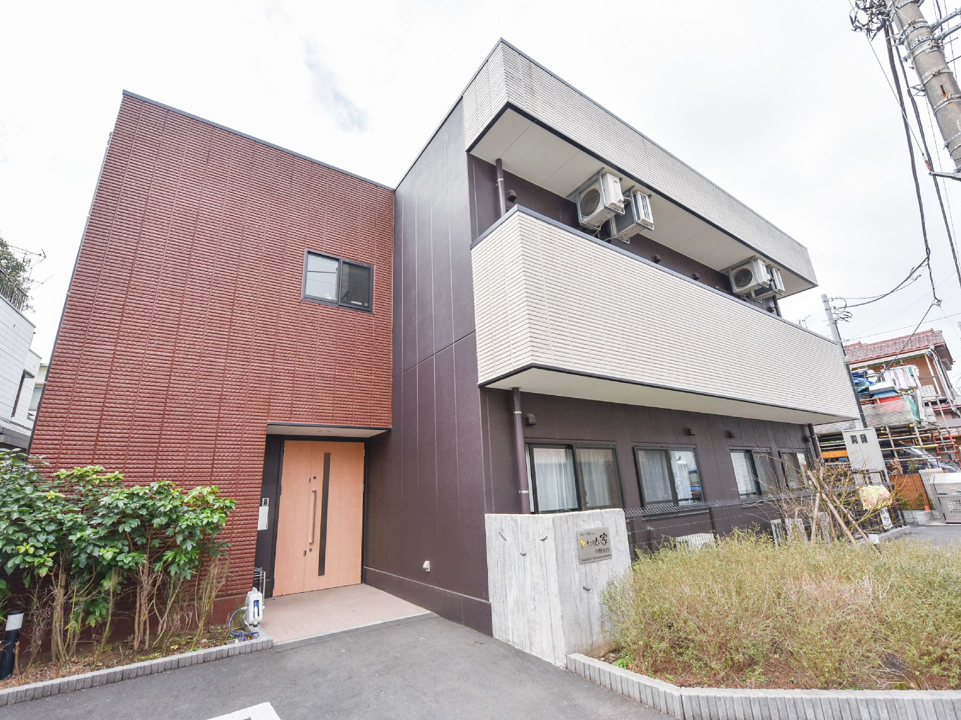 茶色の外装とツートンカラーになったデザイン性の高い建物になっている。木目調の親子ドアがエントランスになっている。